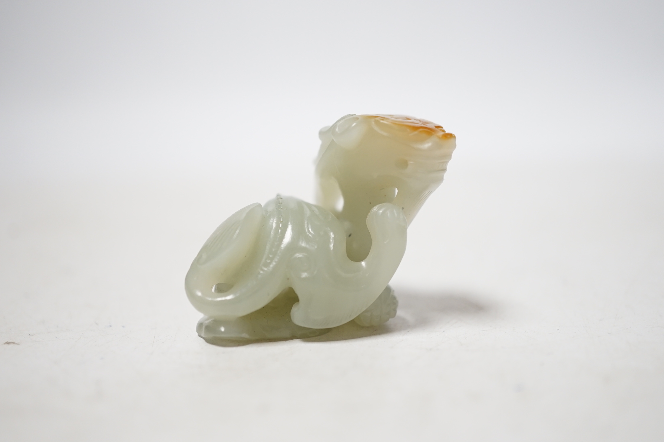 A Chinese pale celadon and russet skin jade figure of a dragon, 4cm high